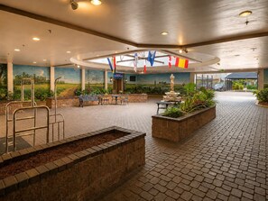 A spacious indoor area with a fountain, seating, and a mural on the walls. - Maison St Charles (New Orleans)
