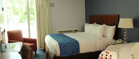 Hotelkamer met een bed, een stoel, een bureau, bureaulamp, telefoon en een badkamer met bad.