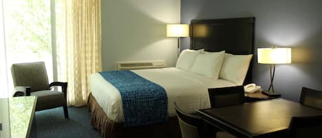 A hotel room with a bed, two bedside lamps, a desk, a chair, and a telephone.