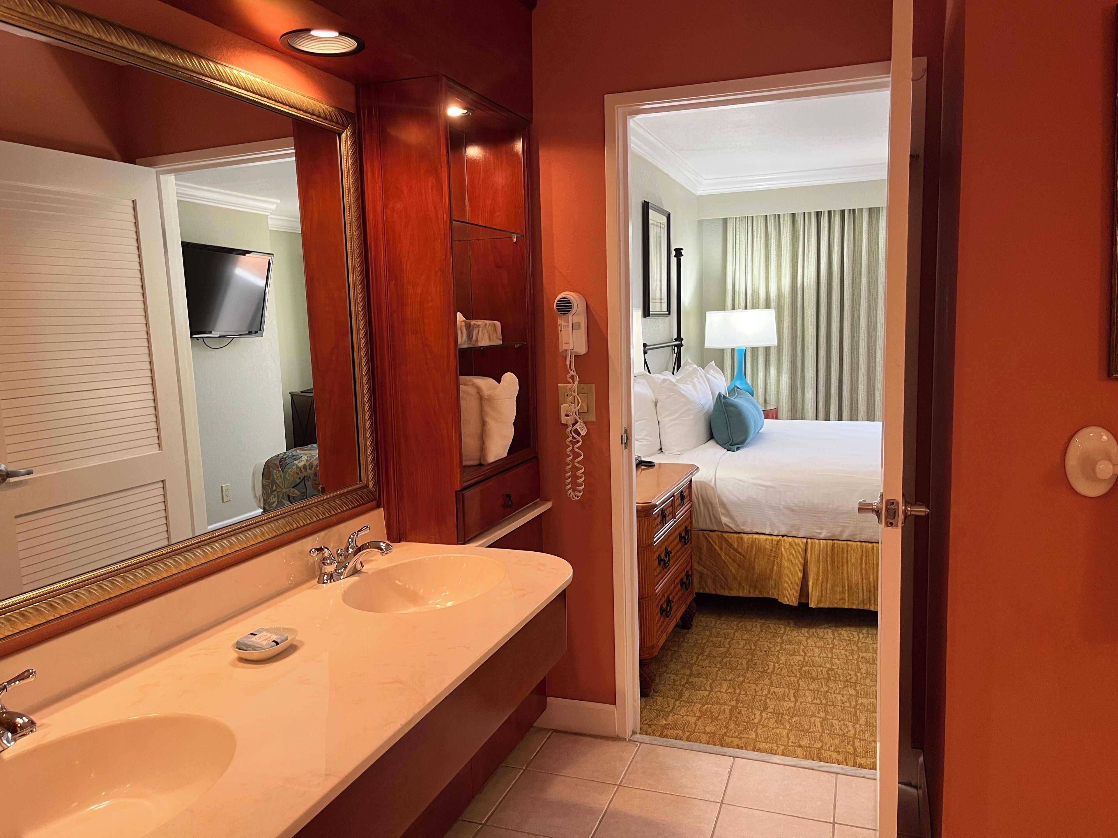 Un baño de hotel con un espejo grande, lavamanos doble y tocador.
