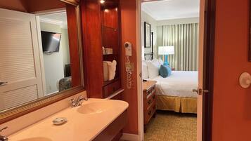 Un baño de hotel con un espejo grande, lavamanos doble y tocador.