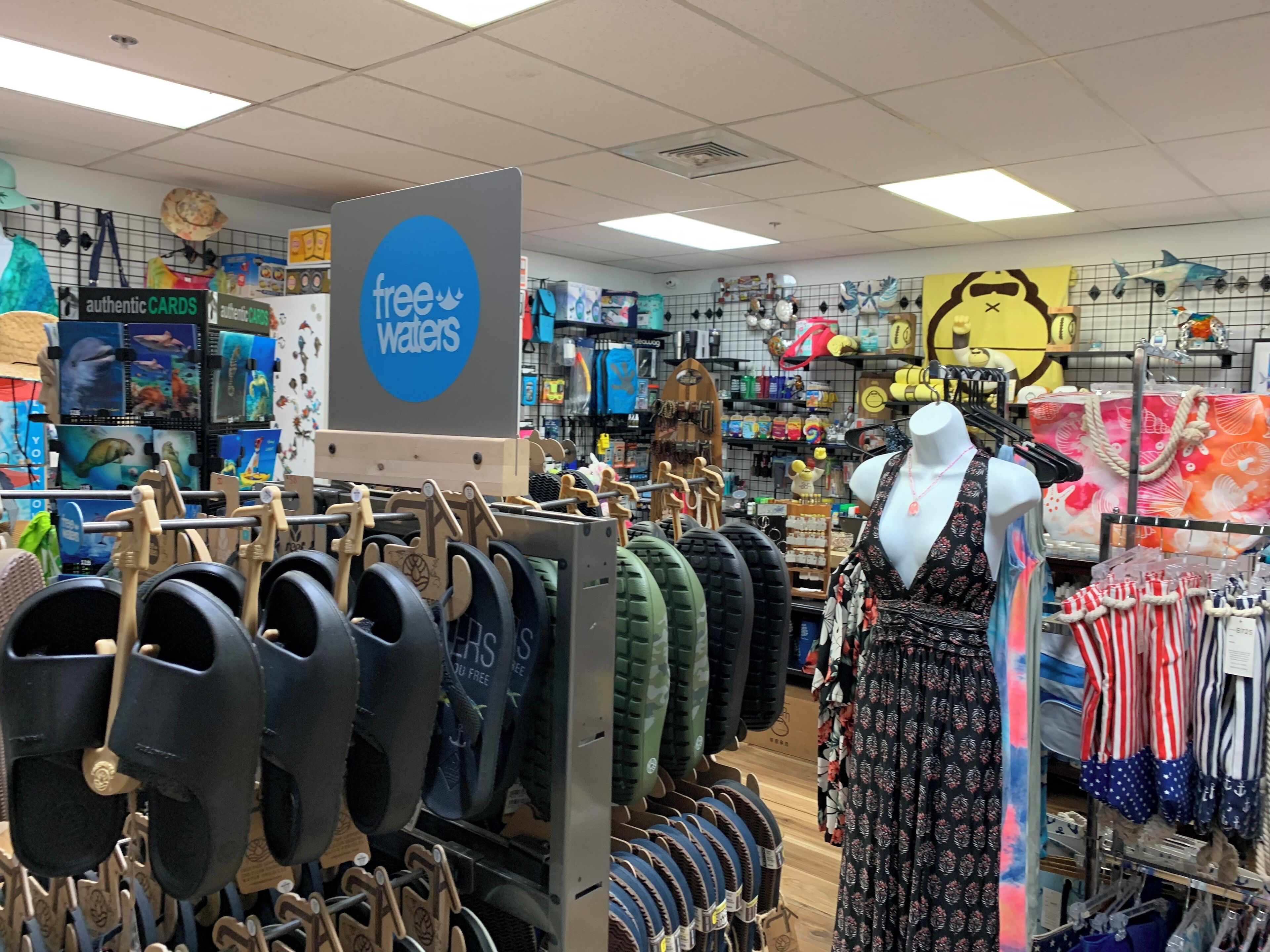 A store with a 'free waters' sign, various bags, and a mannequin in the center.