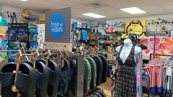 A store with a 'free waters' sign, various bags, and a mannequin in the center.