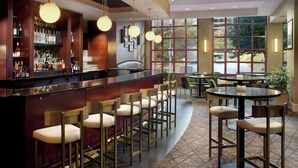 A bar area with stools, a bar counter, and a large window providing a view of the outdoors.