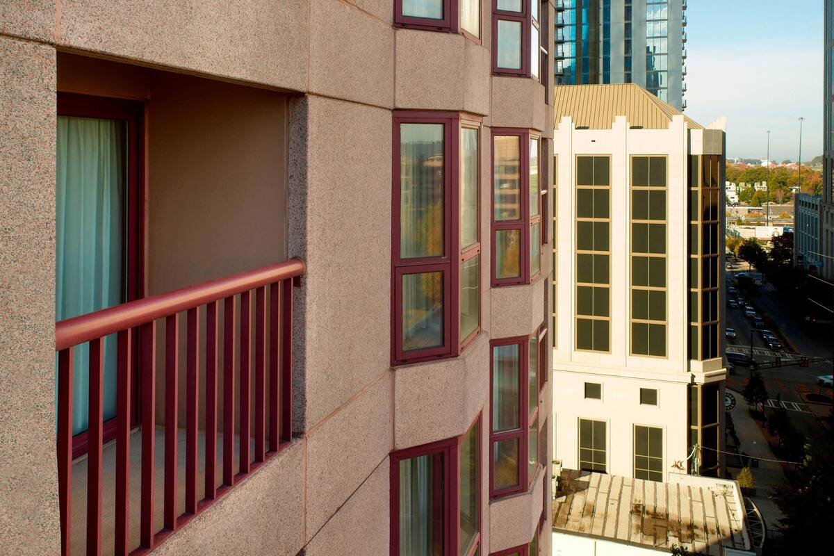 Monikerroksinen rakennus, jonka julkisivu on beige, siinä on suuret ikkunat ja parvekkeessa punainen kaide.