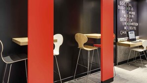 A modern workspace with a black and red color scheme, featuring a desk with a laptop, a chair, and a wall with text about social business. - ibis Paris Père Lachaise (Paris)