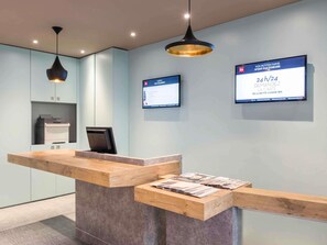 A reception desk with a wooden counter and a digital display board. - ibis Paris Père Lachaise (Paris)