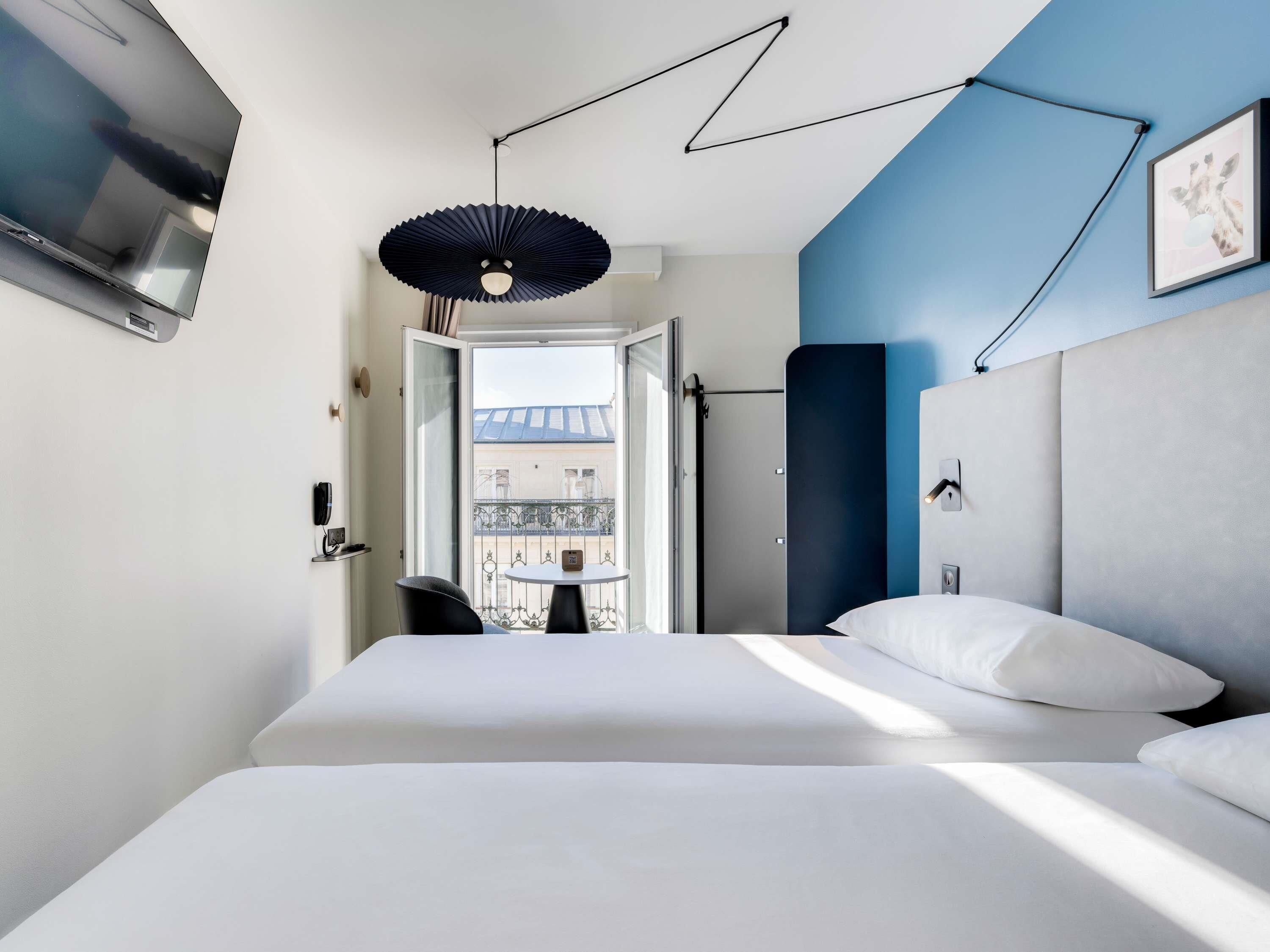 Een moderne hotelkamer met een bed, een bureau en uitzicht op een balkon.