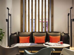 A modern lounge area with a sofa and two tables, wooden slats on the wall, and floor lamps. - ibis Paris Père Lachaise (Paris)