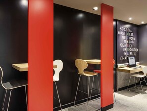 A modern workspace with a black and red color scheme, featuring a desk with a laptop, a chair, and a wall-mounted computer. - ibis Paris Père Lachaise (Paris)