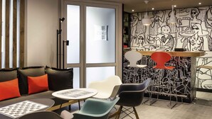 A modern lounge area with a sofa, chairs, a table, and a mural on the wall. - ibis Paris Père Lachaise (Paris)