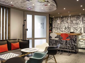 Un área de estar moderna con un sofá, sillas, una mesa y un mural en la pared.