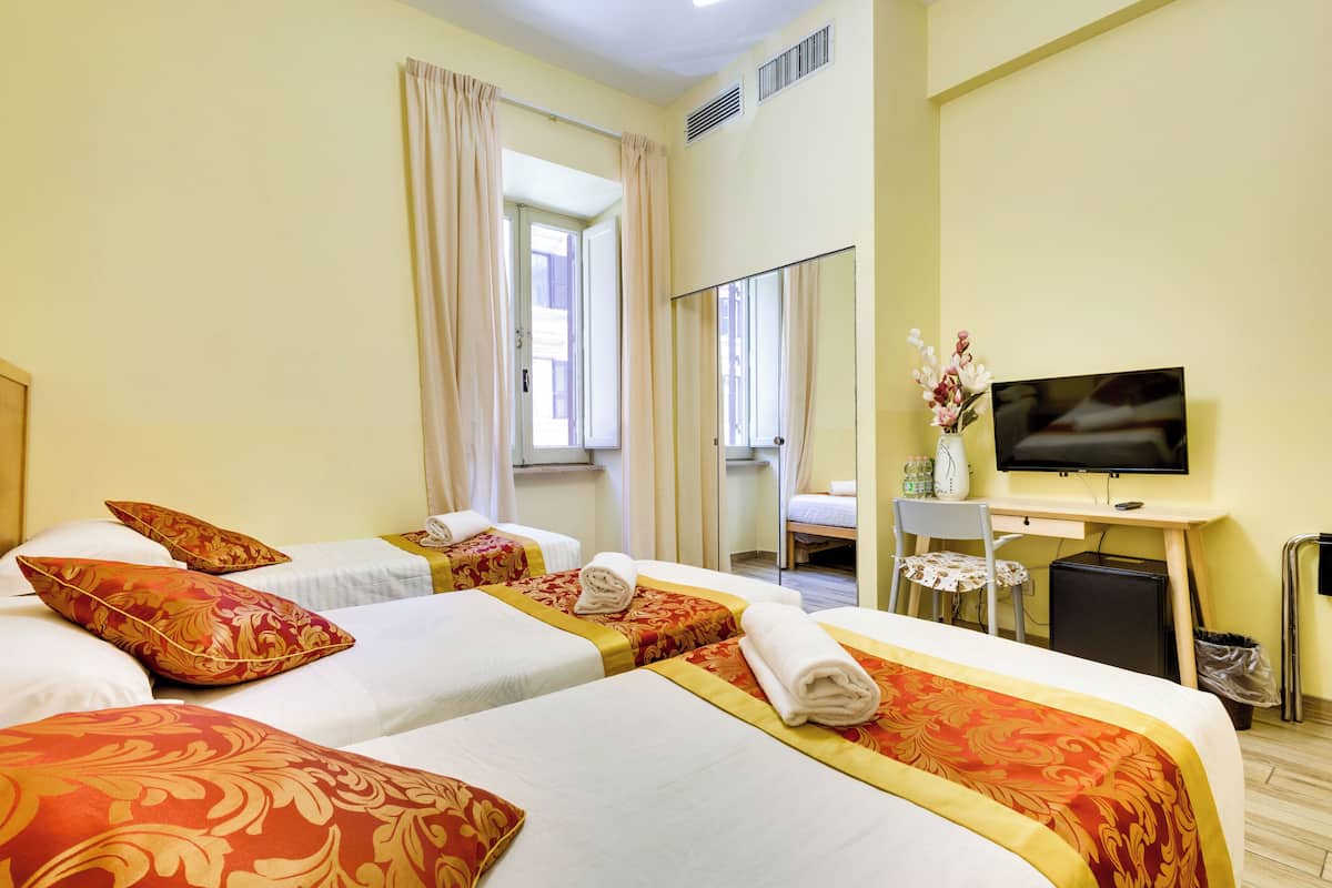 Une chambre d’hôtel avec deux lits, un bureau avec une télévision, une chaise et une petite table.