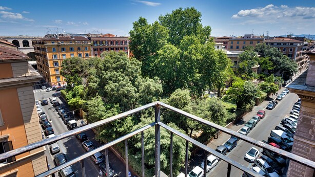 A high-rise building with multiple floors, a parking lot, and surrounding trees. - Hotel Terminal (Rome)