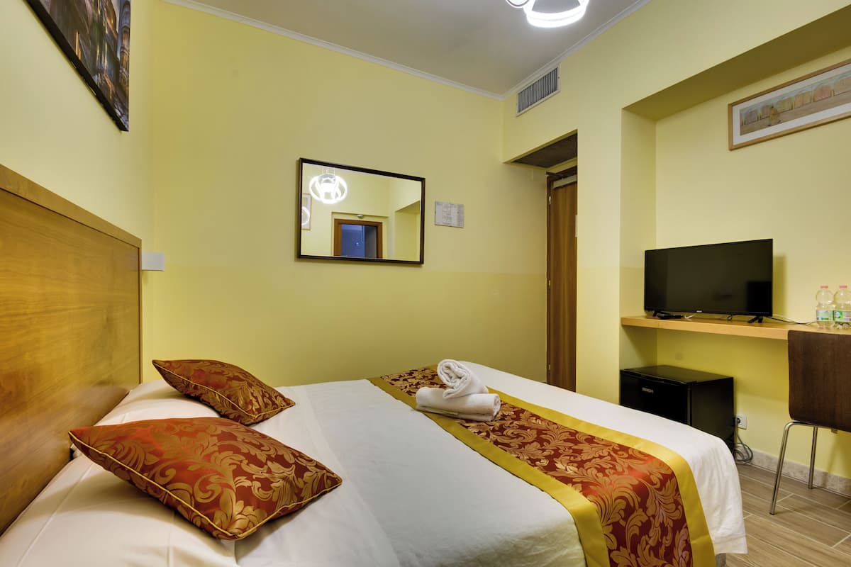 Une chambre d’hôtel avec un lit, une télévision, un bureau et une chaise.