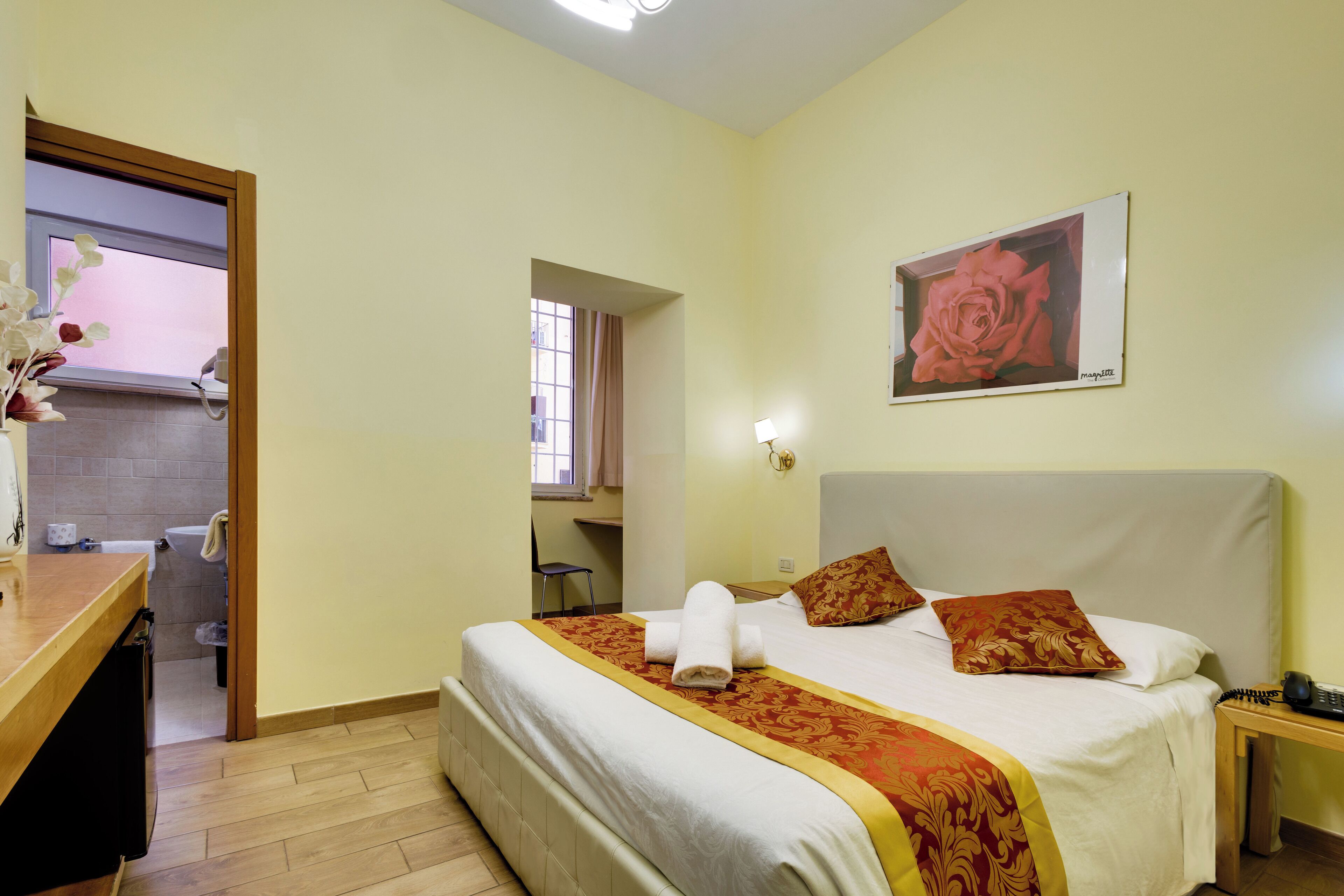 A hotel room with a bed, a desk, and a bathroom visible through an open door.