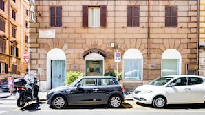 A multi-story building with a red facade, multiple windows with shutters, and a balcony on the upper floor. - Hotel Terminal (Rome)