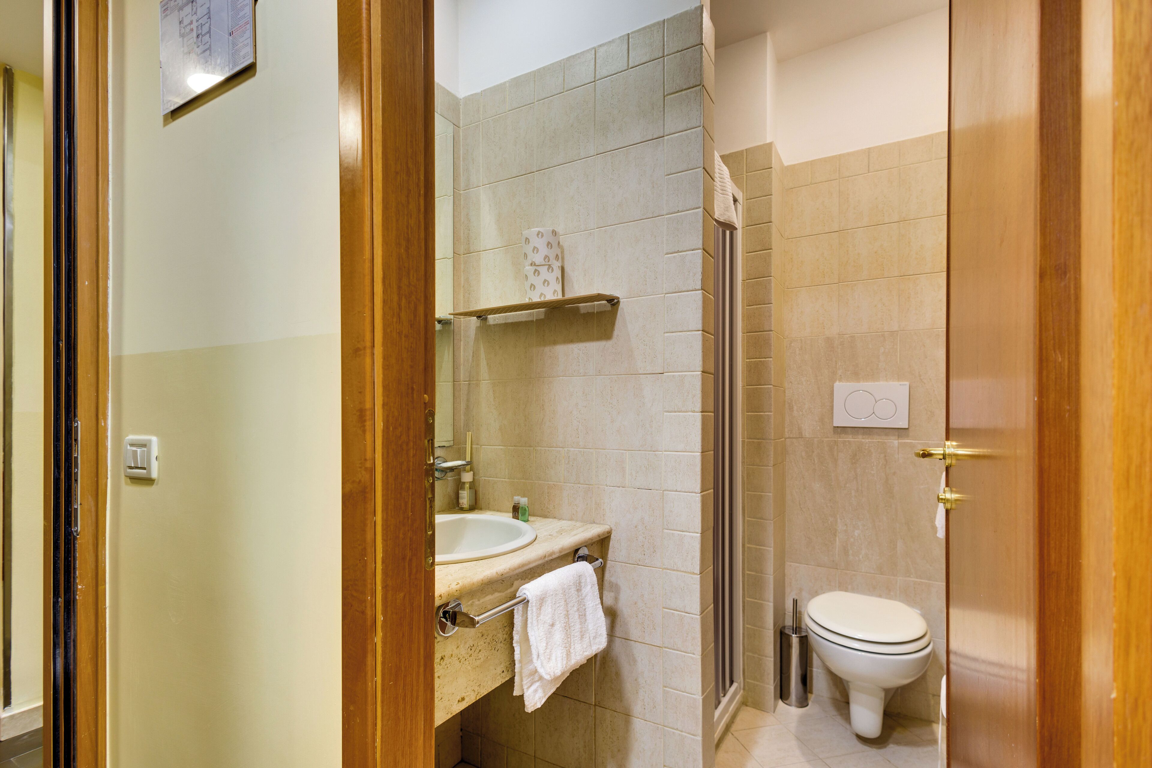 A bathroom with a sink, mirror, towel rack, toilet, and shower.