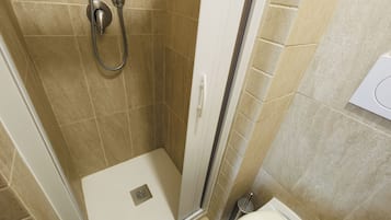 Ducha con cabezal de ducha de mano y desagüe en el suelo.