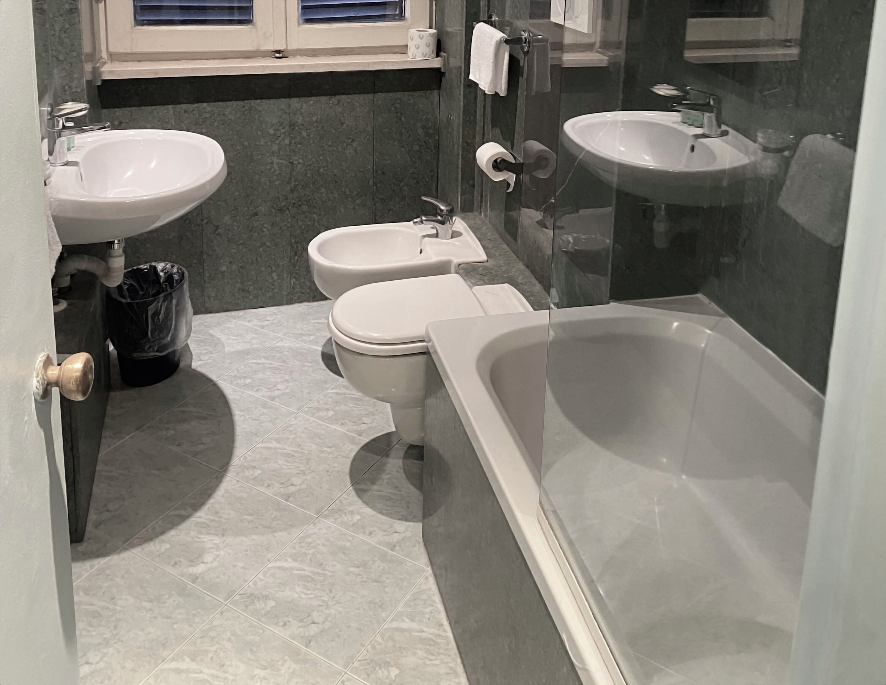 A modern bathroom with a bathtub, two sinks, a toilet, and a bidet.