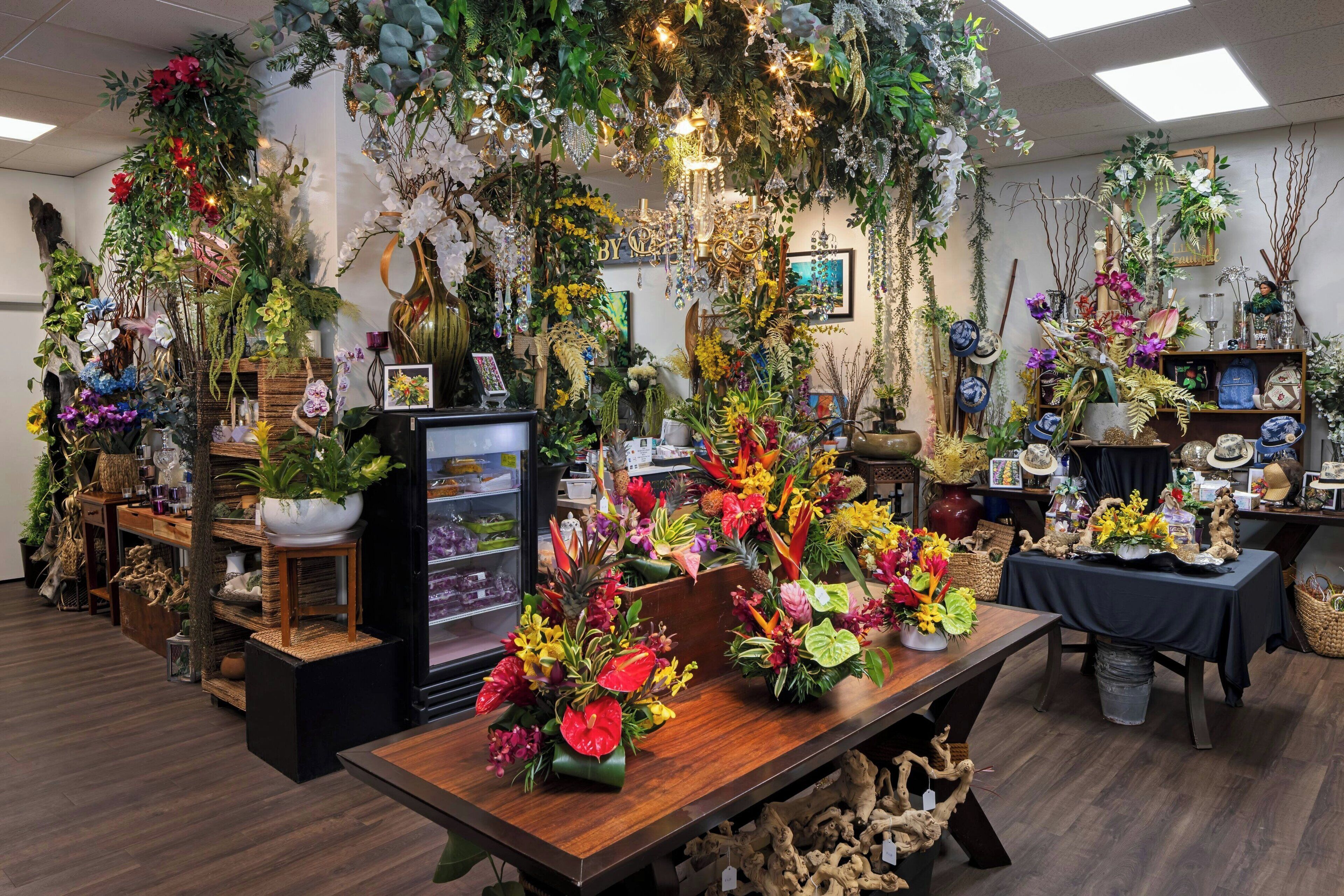 A floral shop with various plants and flowers displayed on tables and shelves.