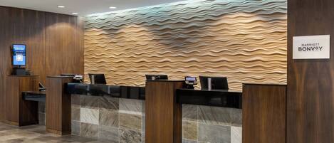 A reception area with a wavy wall design, a digital screen, and a sign for Marriott Bonvoy.