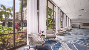 Un hall d’hôtel doté de grandes fenêtres, d’un tapis à motifs bleus et de plusieurs espaces aménagés pour s’asseoir.