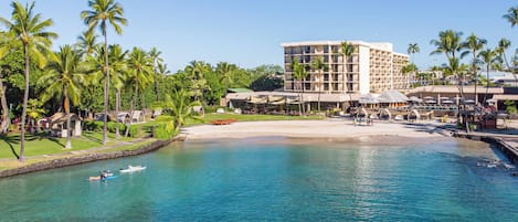 Un resort con piscina cristalina, palmeras y un edificio con varios balcones.