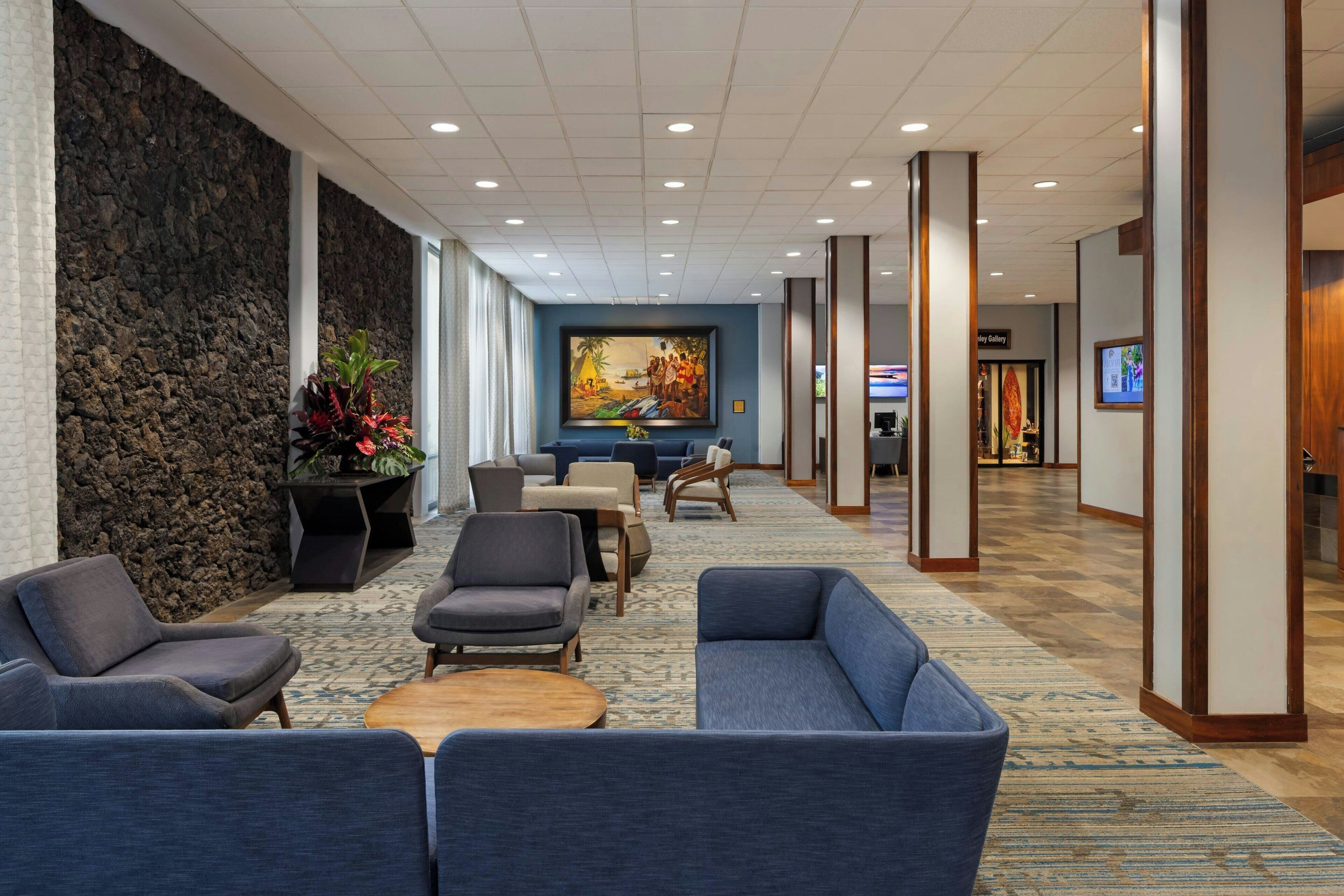 A lobby with seating, a stone wall, a painting, and a reception area.