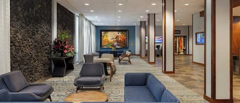 A lobby with seating, a stone wall, a painting, and a reception area.