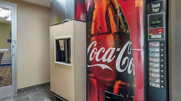 A Coca-Cola vending machine in a hotel lobby with a water dispenser and a "Thank You!" sign.