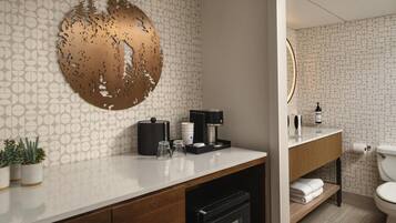 Une salle de bain moderne avec un mur orné d’un motif, un élément décoratif rond, une machine à café et des toilettes.