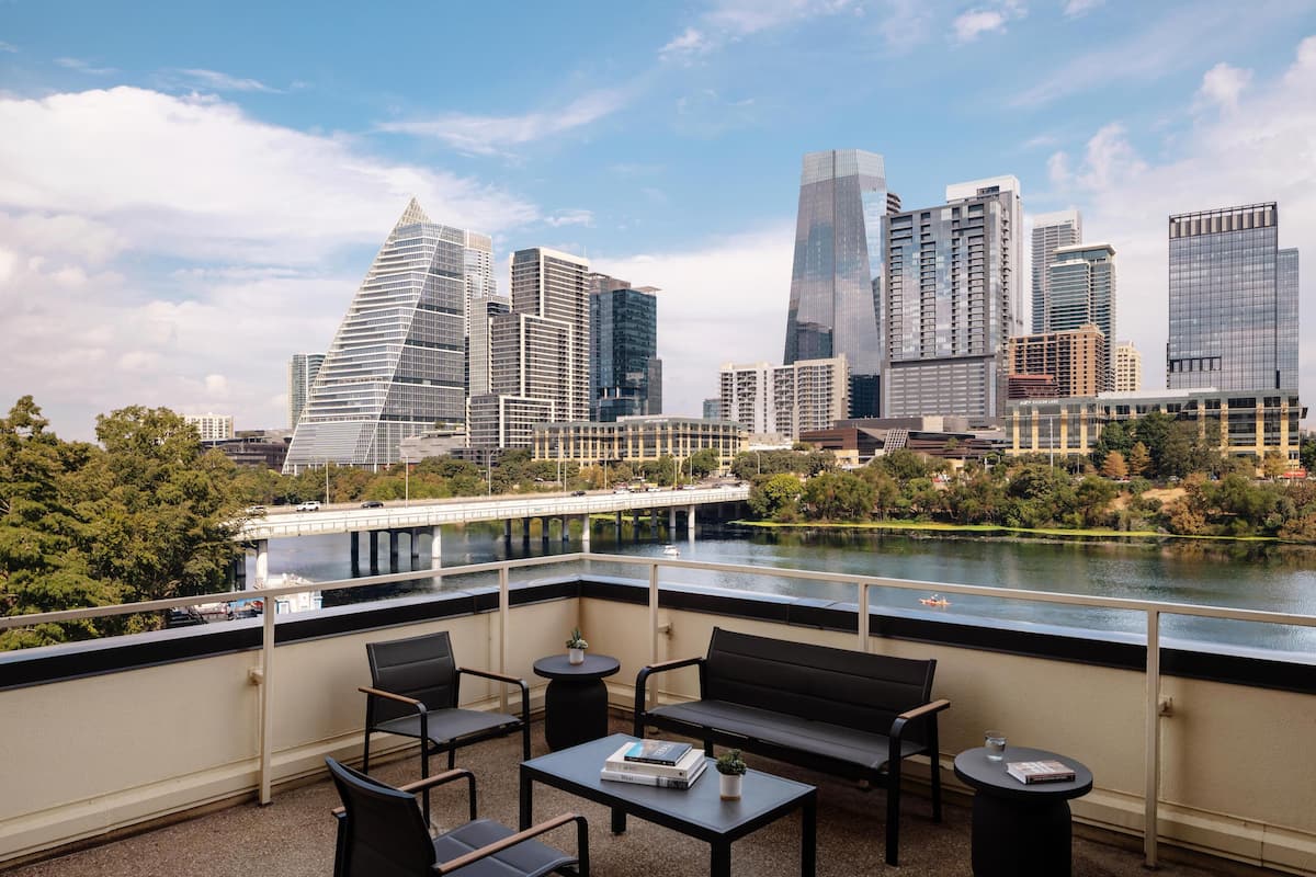 A balcony with a view of a city skyline, a river, and a bridge.