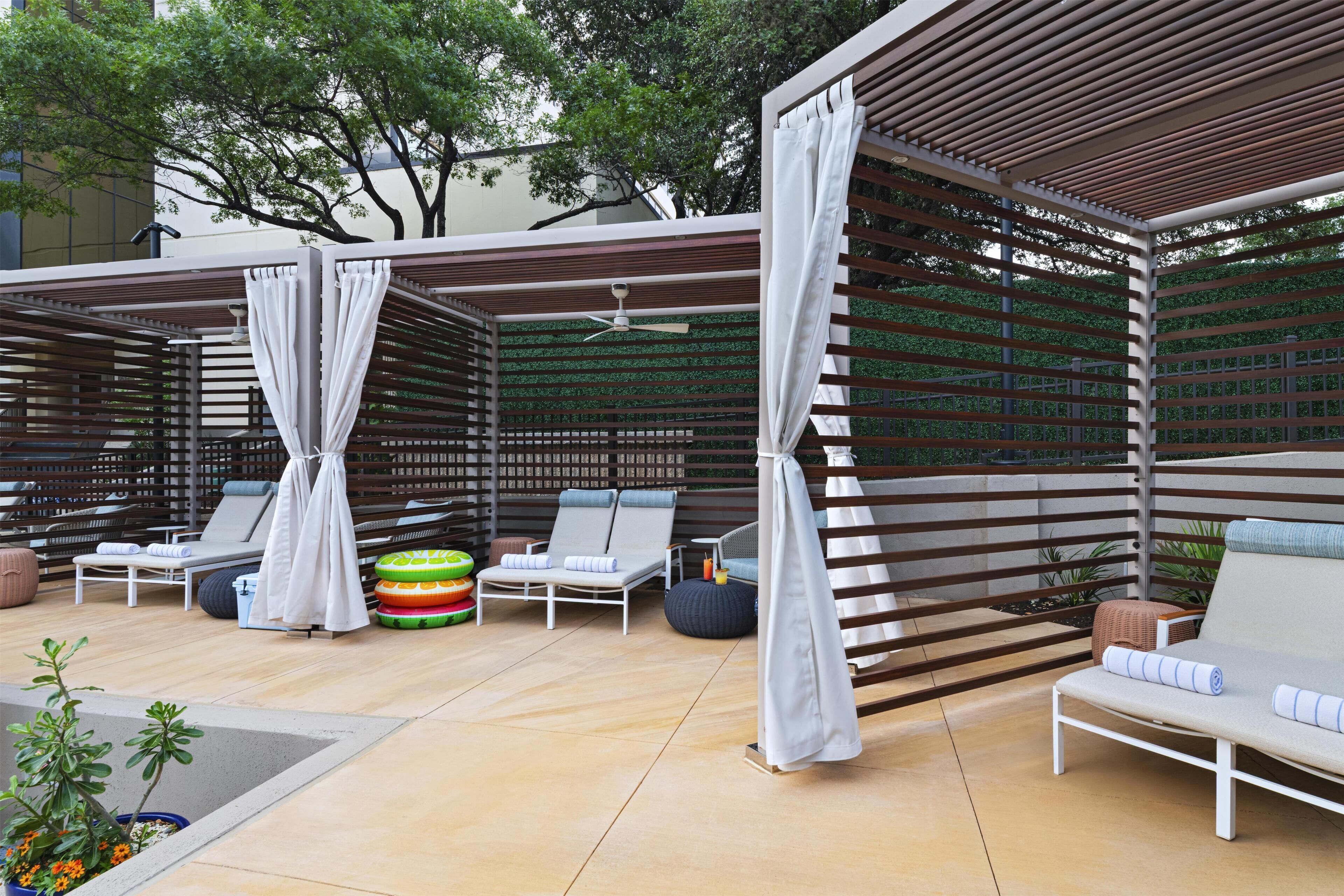 An outdoor seating area with lounge chairs, a ceiling fan, and a decorative wall.