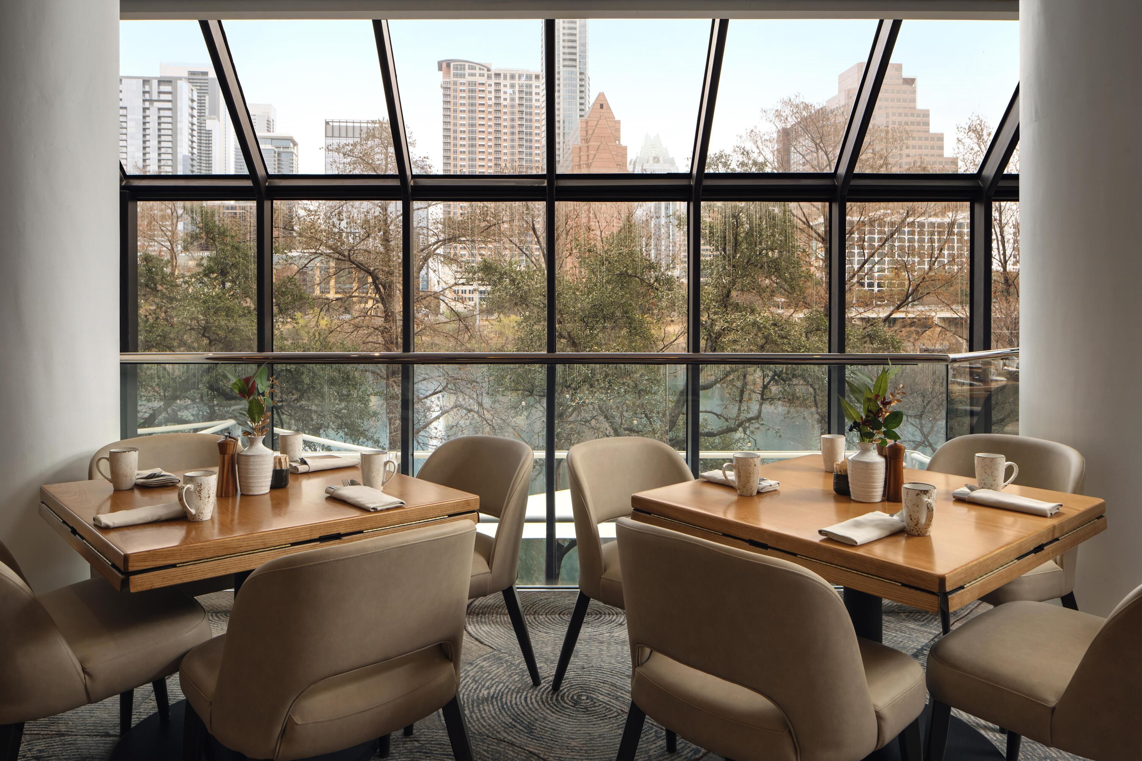 A conference room with a large window, multiple tables, and chairs.