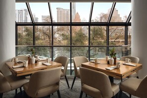 A conference room with a large window, multiple tables, and chairs. - Hyatt Regency Austin (Austin)