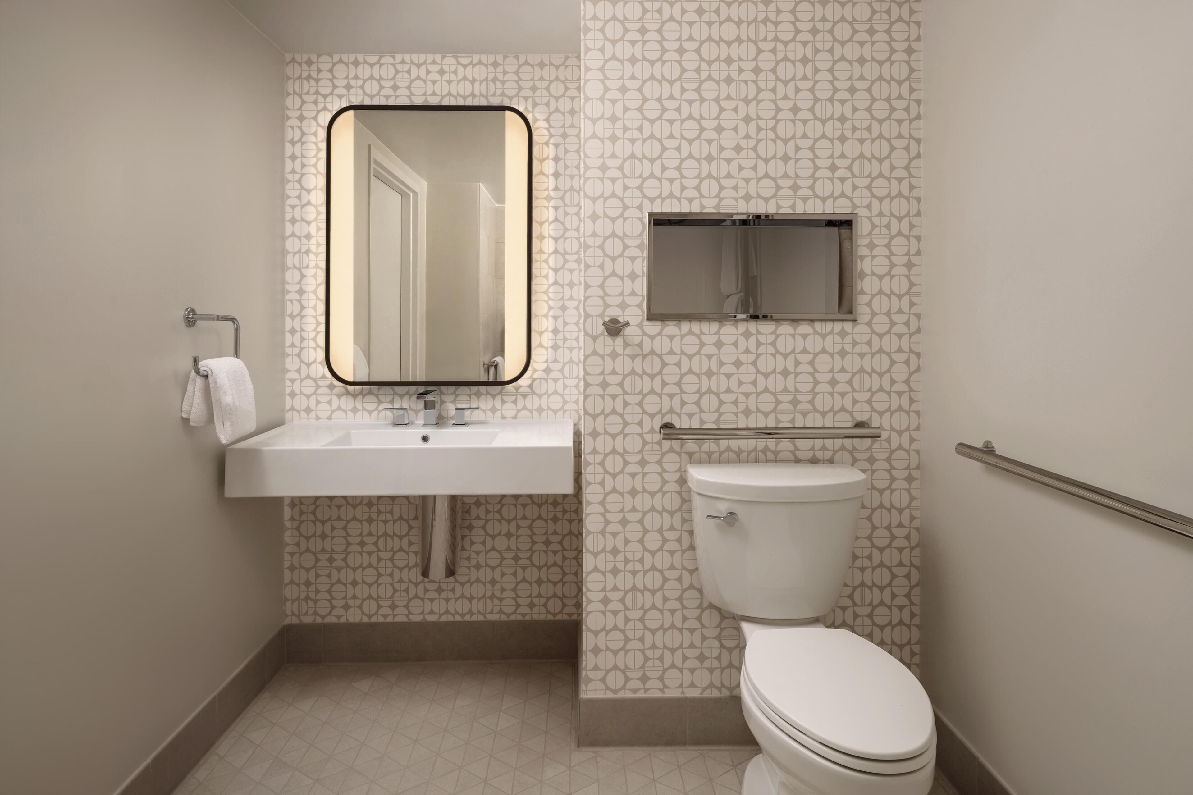 A bathroom with a toilet, sink, and mirror.