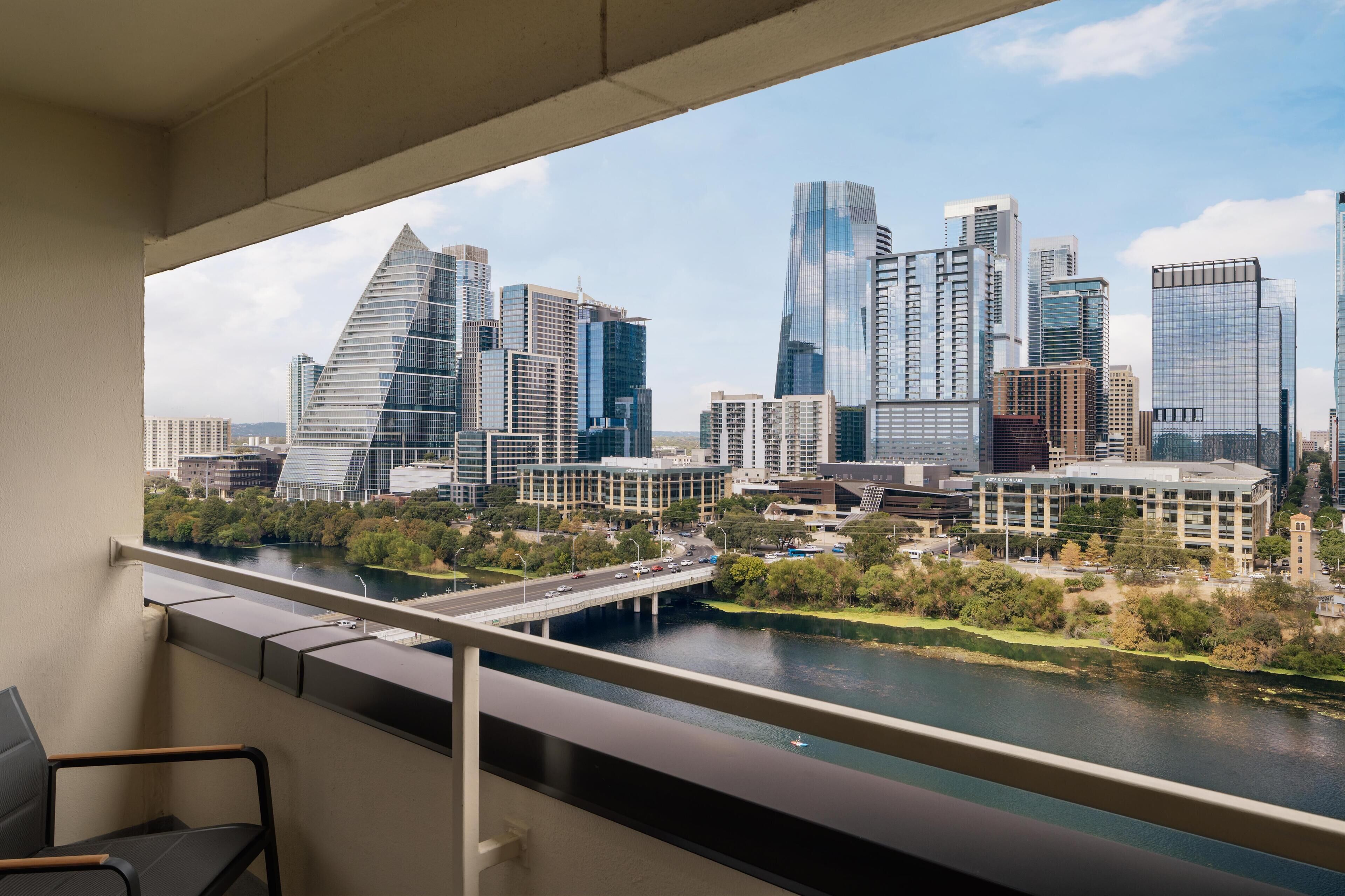 A cityscape with modern buildings, a river, and a bridge.