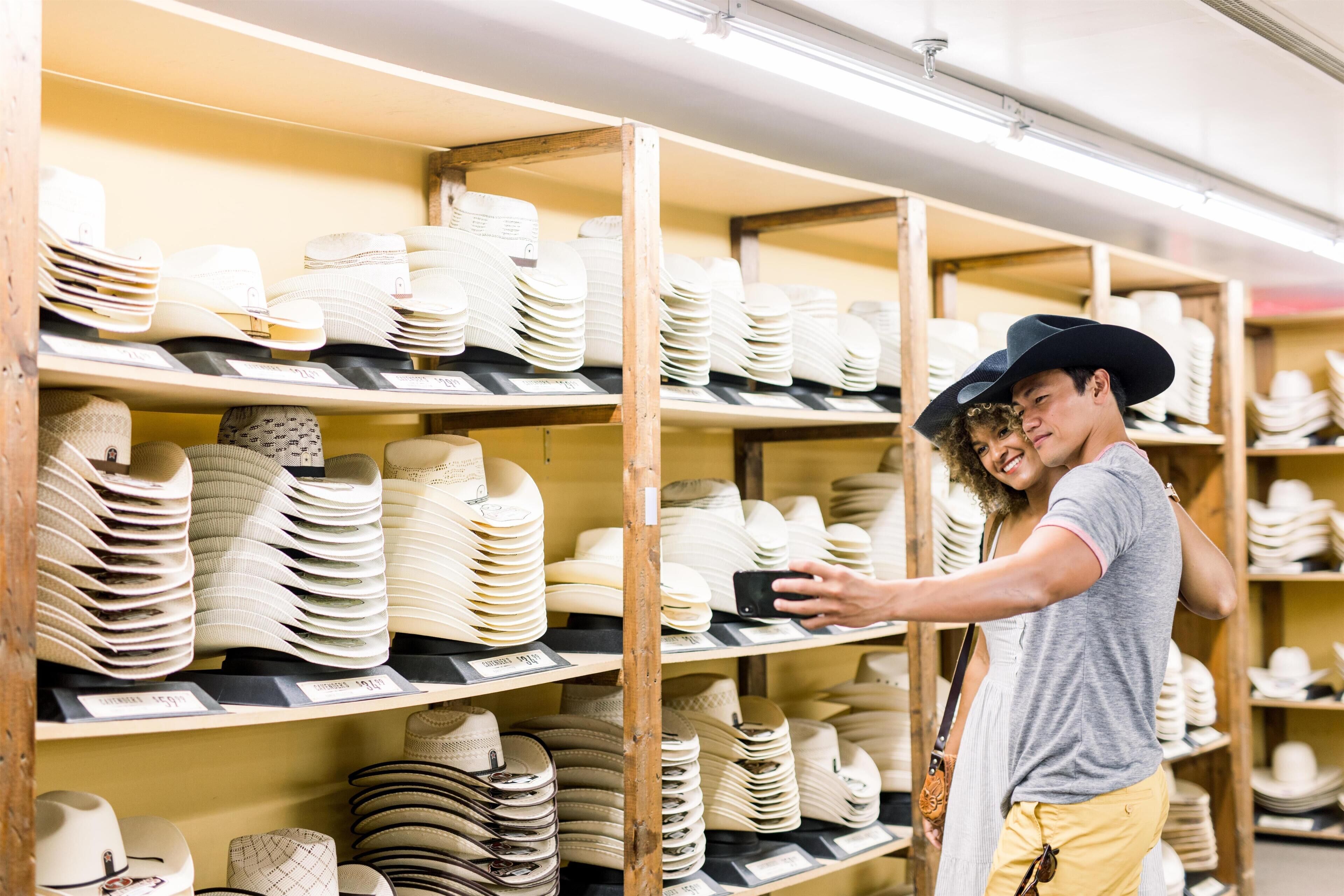 A person browsing through a store with shelves of hats and headwear.