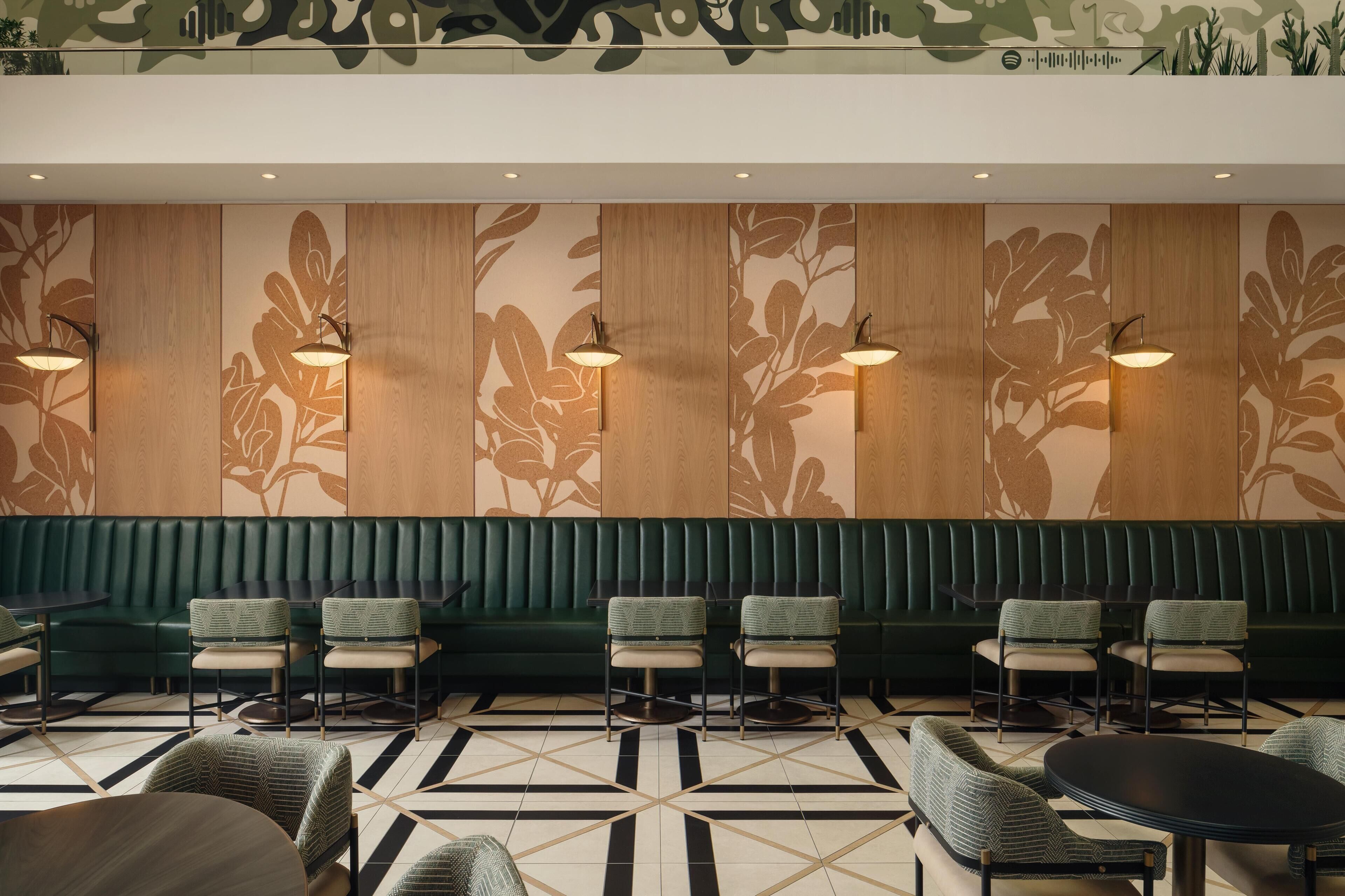 A modern interior with a green upholstered bench seating area, patterned wall panels, and a geometric floor design.