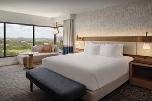 A hotel room with a large bed, a sofa, a small table, and a bench. - Hyatt Regency Austin (Austin)