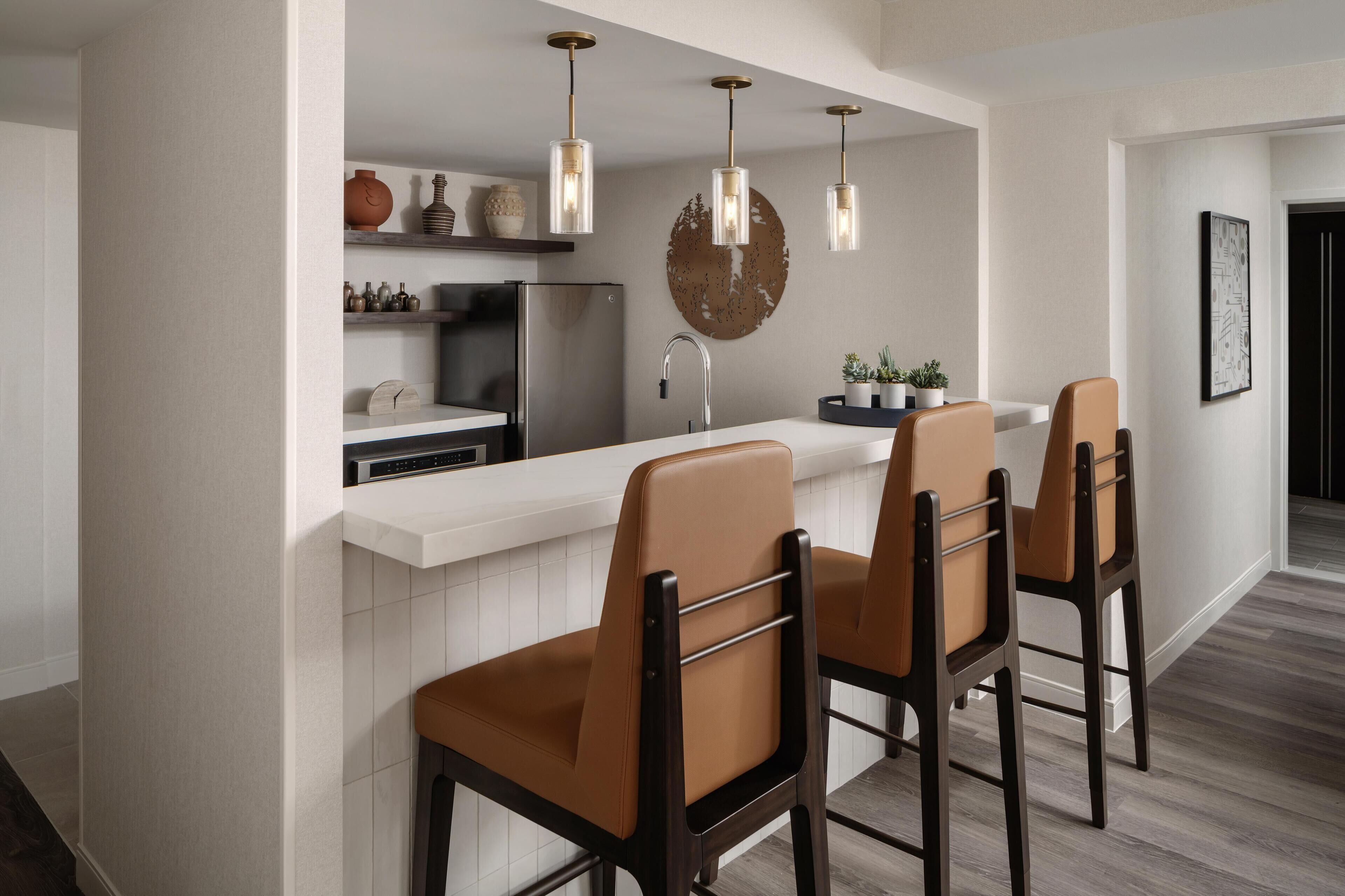 A modern kitchen with a white island, stainless steel appliances, and pendant lighting.