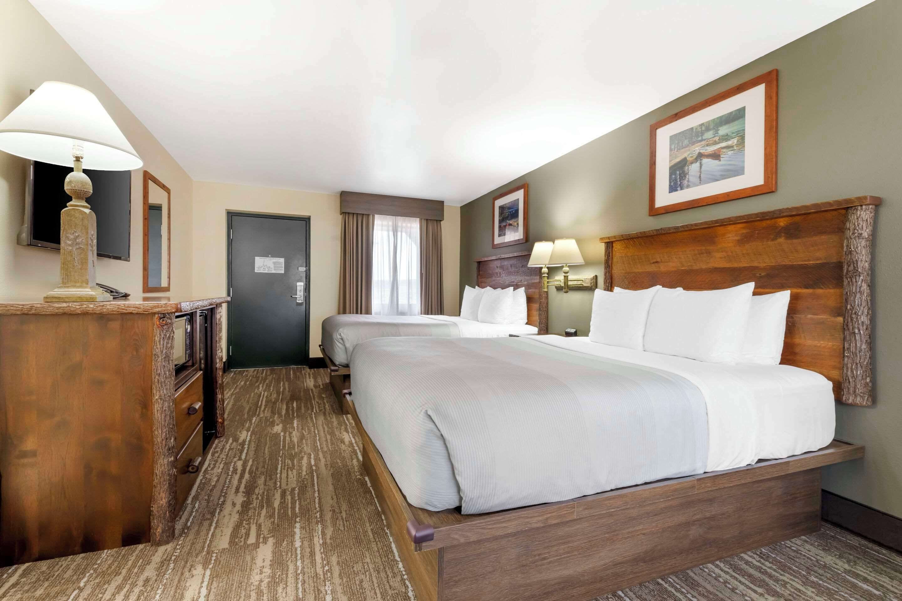A hotel room with a large bed, bedside tables, a desk, and a television.