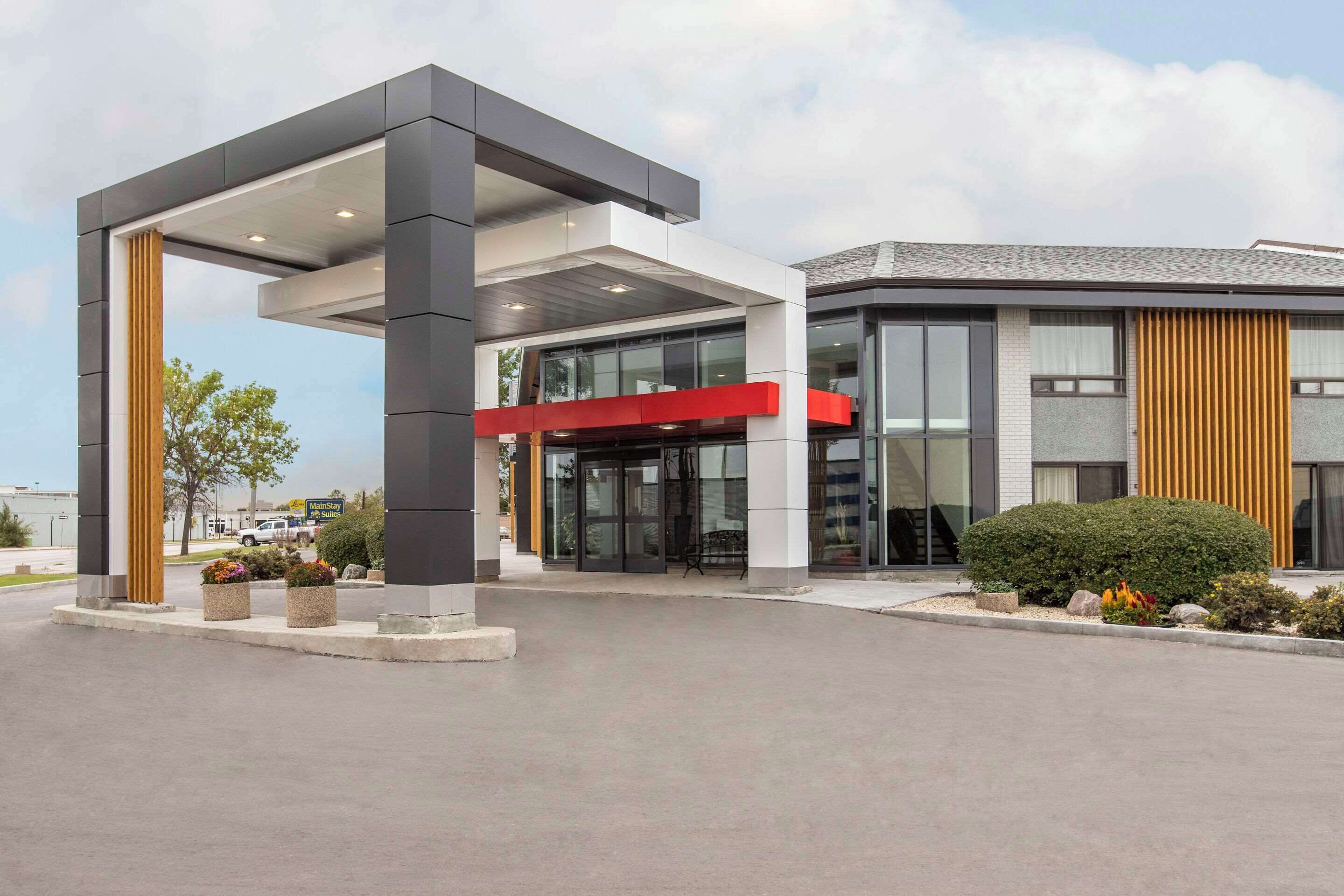 A modern building with a covered entrance, large windows, and a red accent wall.