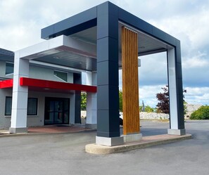 A modern building with a prominent vertical wooden column, a red accent on the facade, and a clear sky in the background. - Comfort Inn Montreal - South Brossard (Brossard)