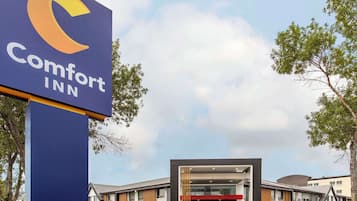 A Comfort Inn hotel entrance with a modern design, featuring a prominent sign and a covered entrance area.
