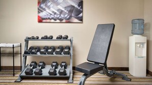 A gym area with a water dispenser, a chair, and a rack of dumbbells. - Super 8 by Wyndham Chambersburg I-81 (Chambersburg)
