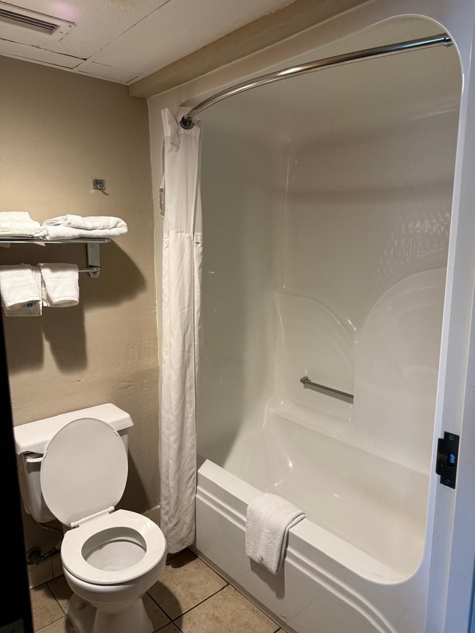 A bathroom with a toilet, a shower with a glass door, and a towel rack with towels.