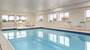 A large indoor swimming pool with clear blue water, surrounded by windows offering views of the outside. - Super 8 by Wyndham Chambersburg I-81 (Chambersburg)