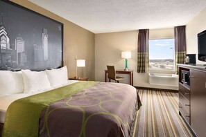A hotel room with a bed, a desk, a chair, a television, a window with curtains, and a cityscape view.